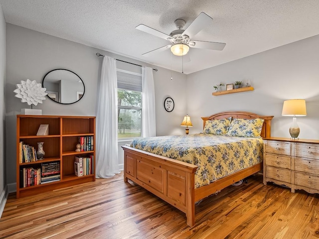 bedroom with hardwood / wood-style floors, a textured ceiling, and ceiling fan