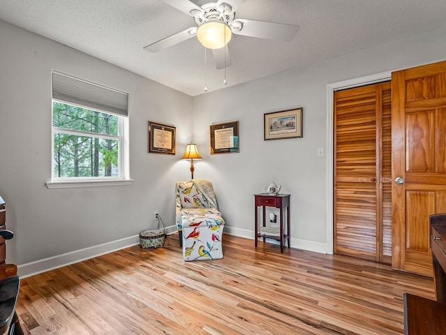 sitting room with ceiling fan, light hardwood / wood-style floors, and a textured ceiling