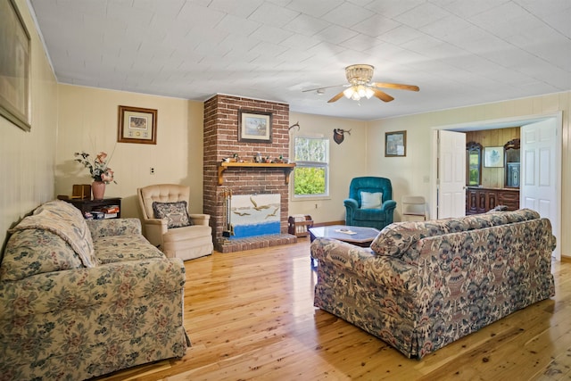 living room featuring a fireplace, ceiling fan, and light wood-type flooring