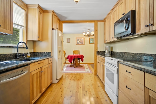 kitchen with dark stone counters, white appliances, sink, and light hardwood / wood-style floors