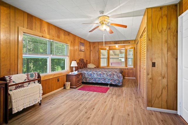 bedroom featuring wood walls, ceiling fan, and light wood-type flooring