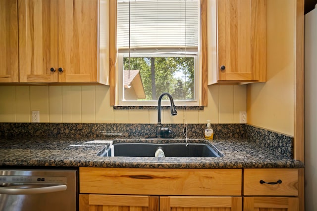 kitchen featuring dishwasher, dark stone counters, and sink