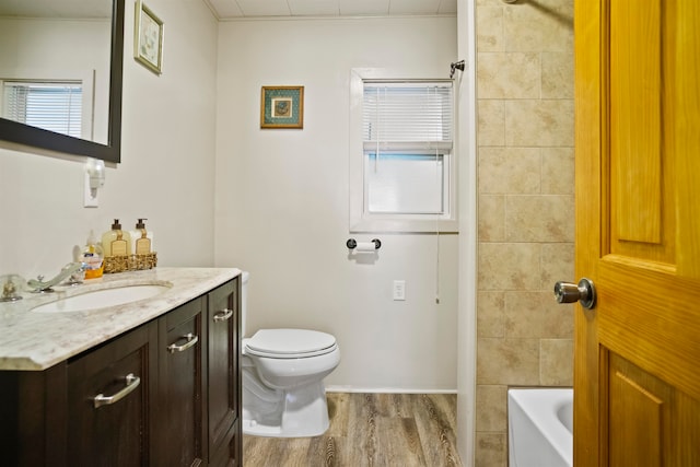 full bathroom with hardwood / wood-style floors, vanity, tiled shower / bath combo, and toilet