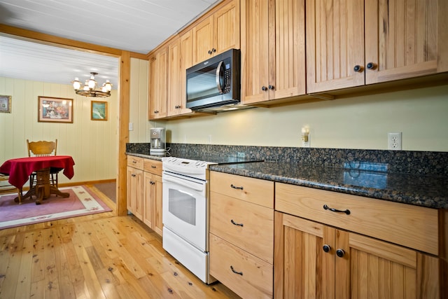 kitchen featuring light hardwood / wood-style floors, light brown cabinets, dark stone countertops, wooden walls, and electric range