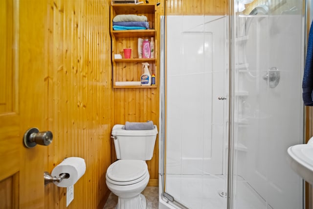 bathroom with tile patterned flooring, wooden walls, toilet, and a shower with door