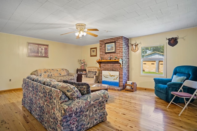 living room with a fireplace, ceiling fan, and light hardwood / wood-style flooring