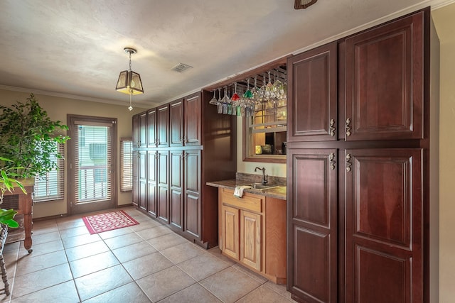 kitchen featuring sink, light stone countertops, ornamental molding, light tile patterned floors, and decorative light fixtures