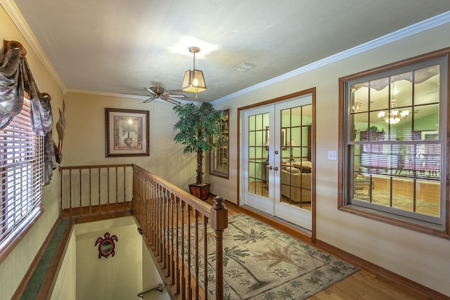 doorway to outside with hardwood / wood-style floors, ceiling fan with notable chandelier, crown molding, and french doors