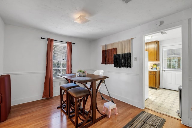 dining space featuring baseboards, a textured ceiling, and light floors