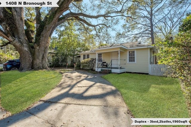 view of front facade with covered porch, fence, and a front lawn