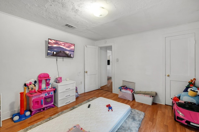 playroom with a textured ceiling, wood finished floors, and visible vents