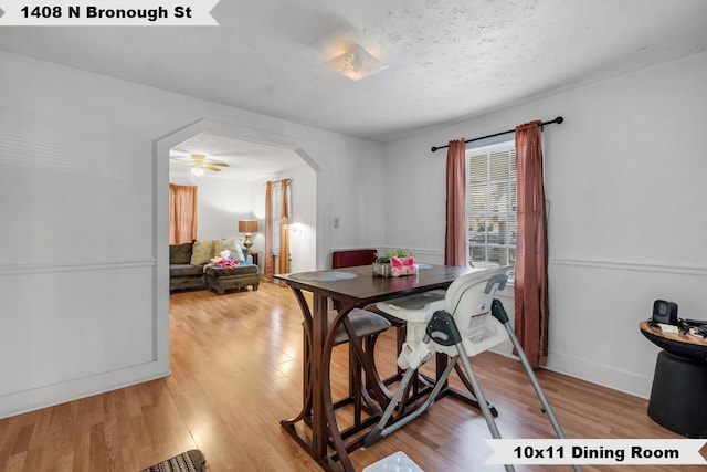 dining area featuring light wood-style flooring, arched walkways, and baseboards