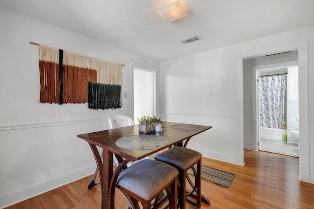 dining room with baseboards, visible vents, and light wood finished floors