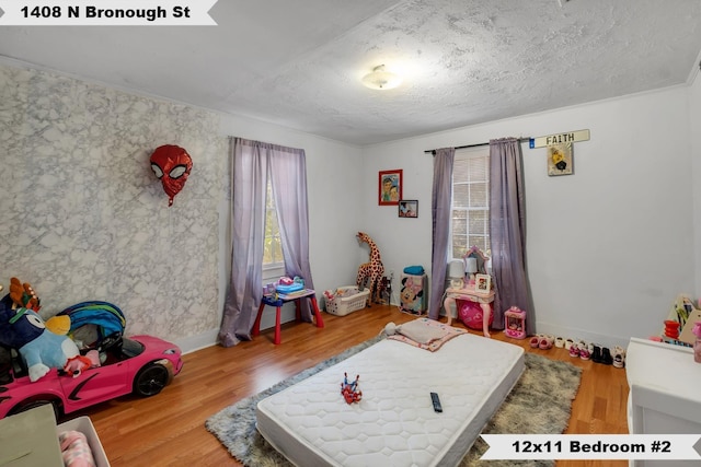 rec room with a textured ceiling, wood finished floors, and baseboards