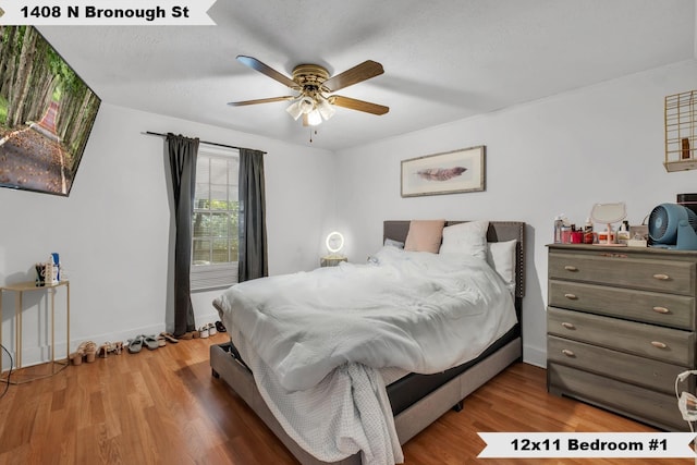 bedroom with a ceiling fan, a textured ceiling, baseboards, and wood finished floors