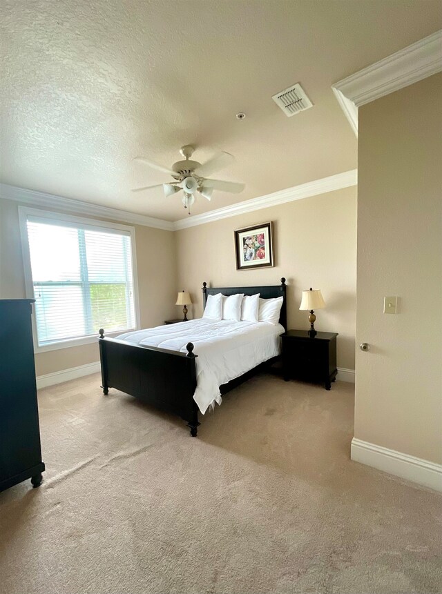 carpeted bedroom with a textured ceiling, ceiling fan, and crown molding