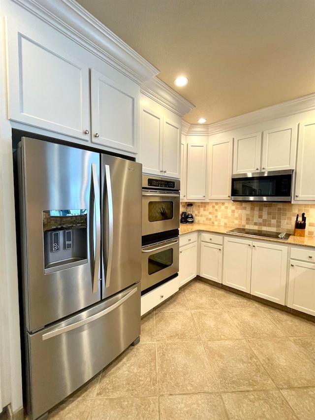 kitchen with light tile patterned flooring, ornamental molding, white cabinetry, appliances with stainless steel finishes, and decorative backsplash