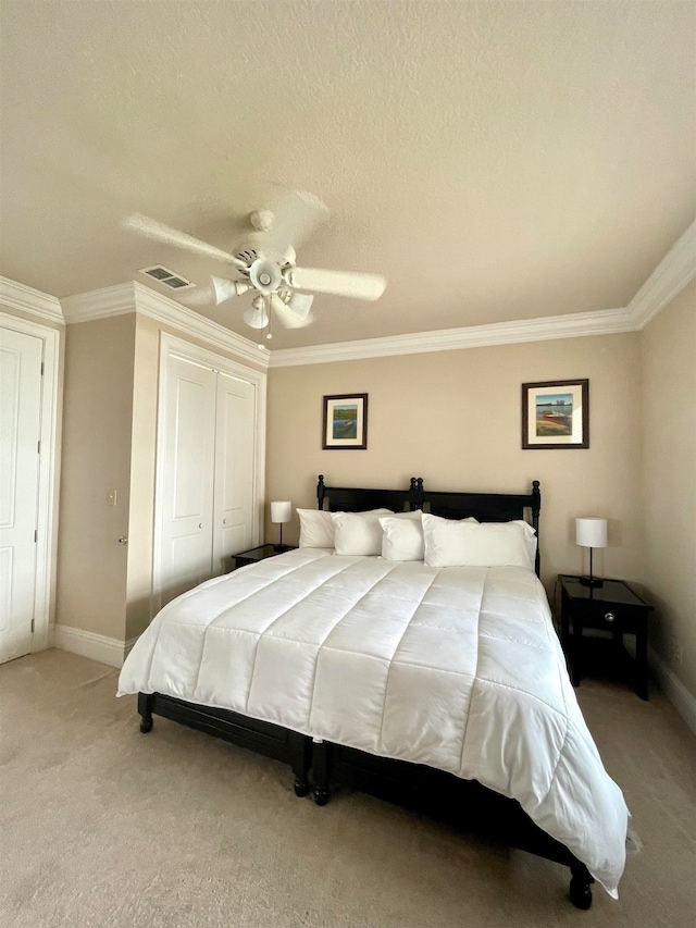 bedroom featuring light colored carpet, a textured ceiling, ceiling fan, crown molding, and a closet