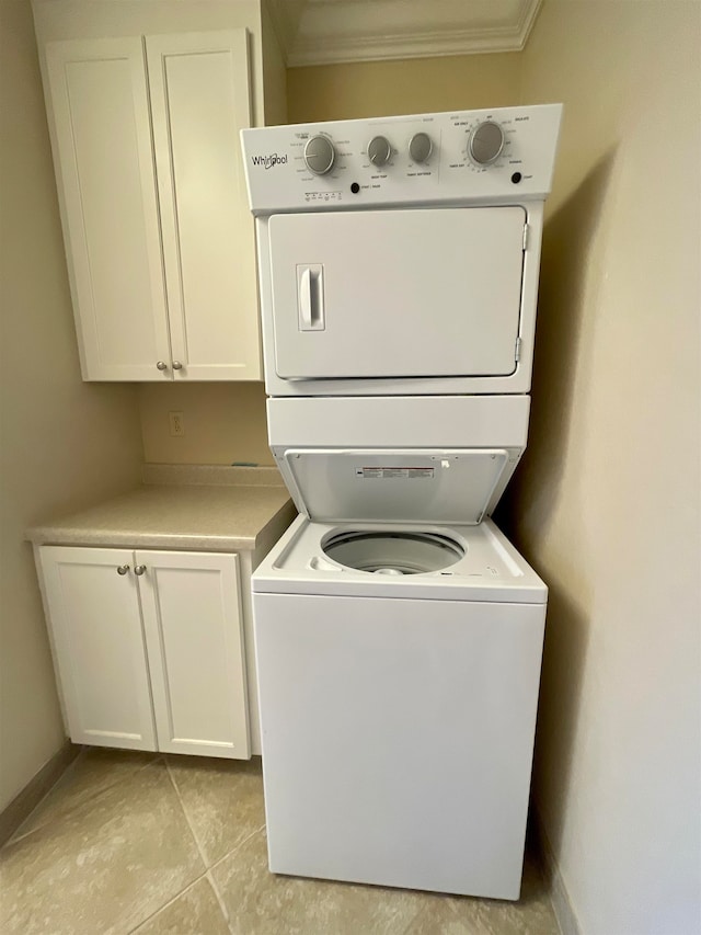 washroom featuring light tile patterned floors, stacked washer / drying machine, and ornamental molding