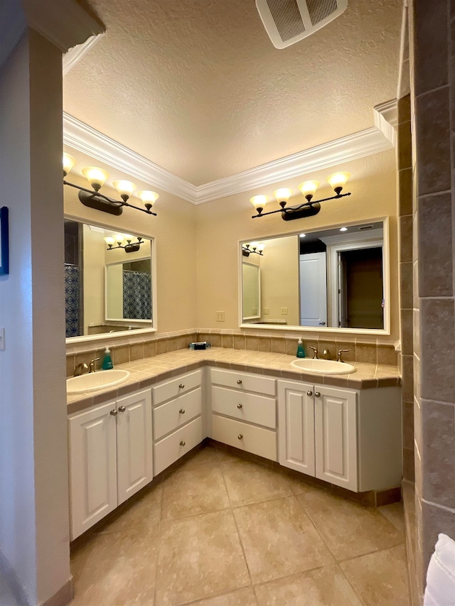 bathroom featuring tile patterned flooring, vanity, a textured ceiling, and crown molding