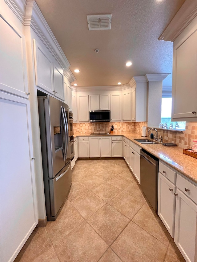 kitchen featuring stainless steel appliances, white cabinetry, sink, and light stone counters