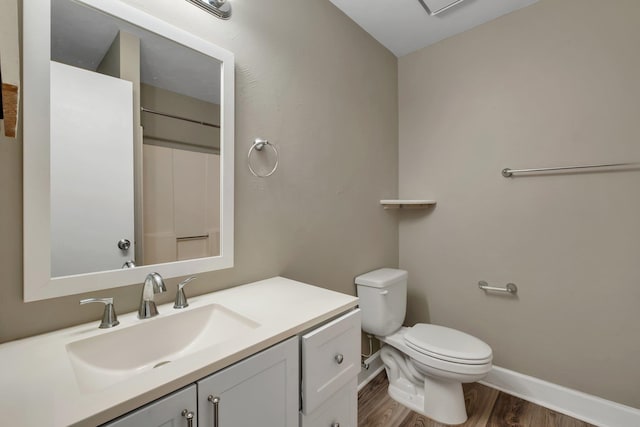 bathroom with toilet, vanity, and wood-type flooring