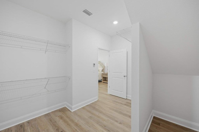 spacious closet with vaulted ceiling and light hardwood / wood-style flooring