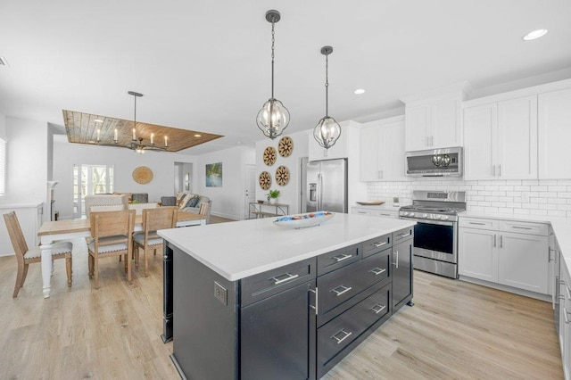 kitchen featuring white cabinets, light wood-type flooring, stainless steel appliances, and pendant lighting