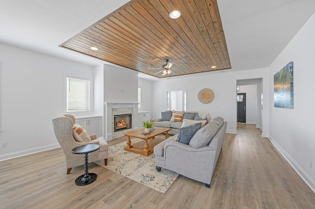 living room with light wood-type flooring, wood ceiling, ceiling fan, and a premium fireplace