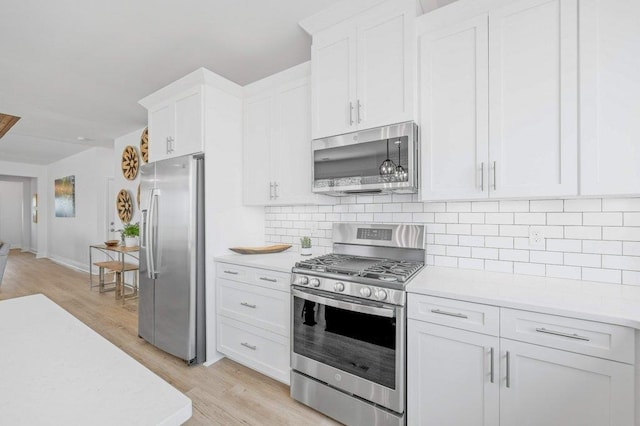 kitchen featuring light hardwood / wood-style flooring, tasteful backsplash, white cabinetry, and stainless steel appliances