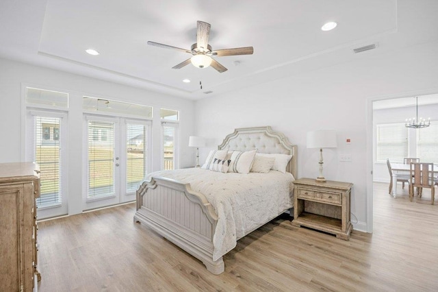 bedroom featuring ceiling fan with notable chandelier, multiple windows, light wood-type flooring, and access to outside