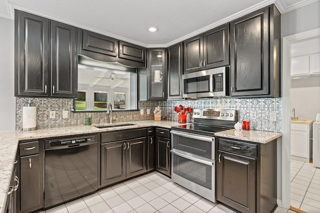 kitchen featuring light tile patterned floors, light stone counters, appliances with stainless steel finishes, a sink, and backsplash