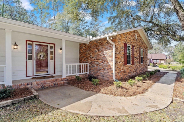 property entrance with covered porch and brick siding