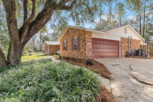 view of home's exterior featuring an attached garage, driveway, central AC, and brick siding