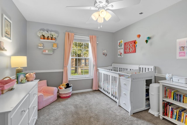 carpeted bedroom featuring ceiling fan, a crib, and baseboards