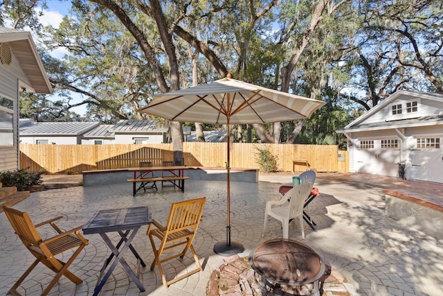 view of patio featuring a garage, an outdoor structure, and a fire pit