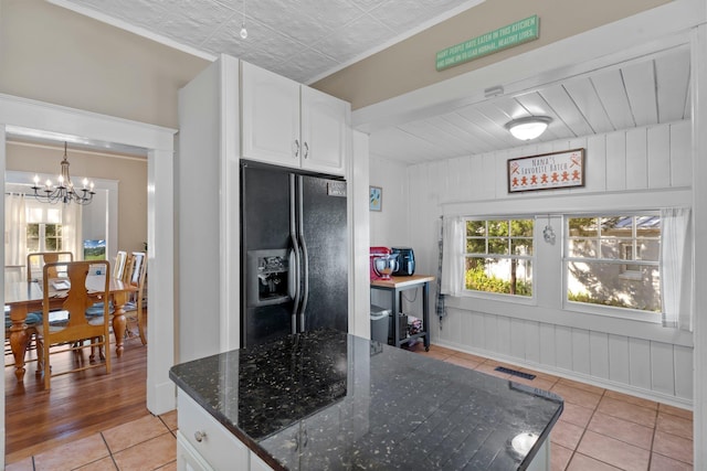 kitchen featuring light tile patterned flooring, white cabinetry, a chandelier, black refrigerator with ice dispenser, and dark stone counters