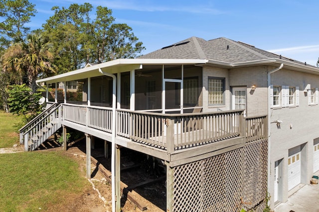 rear view of house featuring a sunroom, a garage, a wooden deck, and a yard