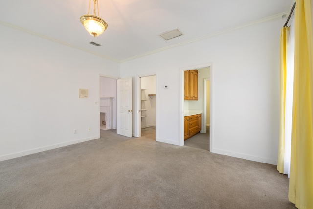 unfurnished bedroom with ornamental molding, light colored carpet, a walk in closet, and connected bathroom