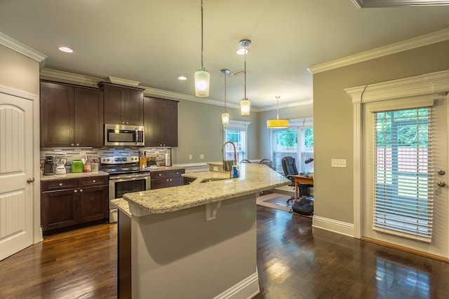 kitchen with a wealth of natural light, appliances with stainless steel finishes, sink, and a kitchen island with sink