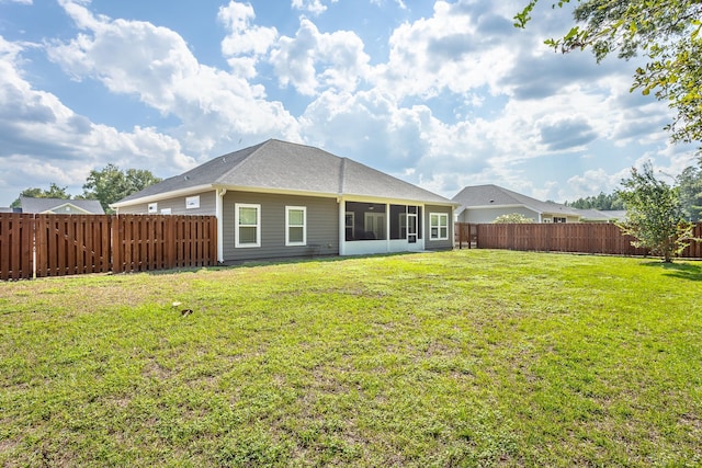 rear view of house featuring a lawn and a sunroom