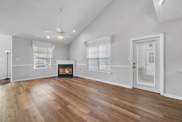 unfurnished living room featuring a wall mounted AC, wood-type flooring, a premium fireplace, and ceiling fan