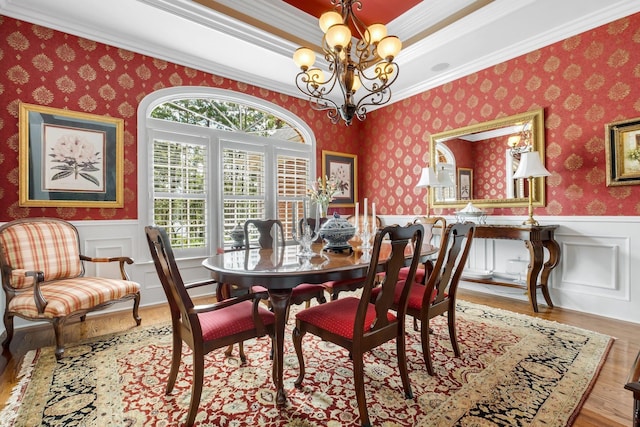 dining space featuring ornamental molding, a healthy amount of sunlight, an inviting chandelier, and light hardwood / wood-style flooring