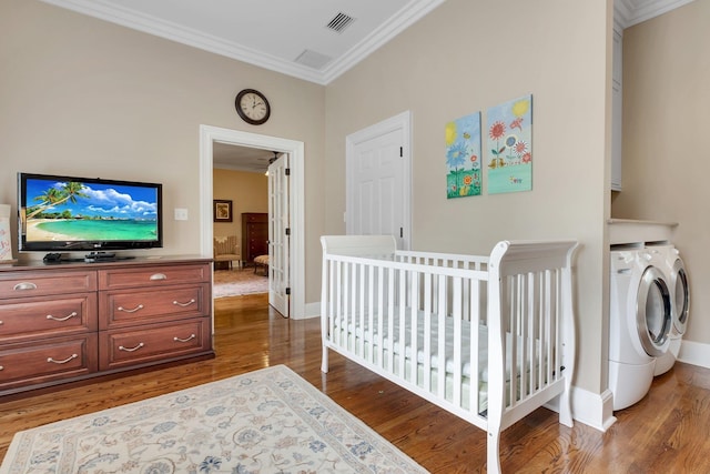 bedroom featuring crown molding, washing machine and dryer, and hardwood / wood-style flooring