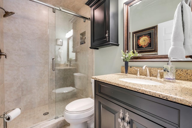 bathroom featuring vanity, a shower with shower door, and toilet