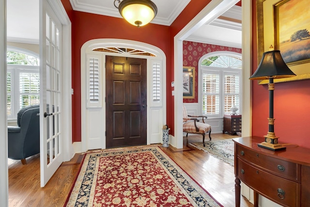 foyer entrance with crown molding, a healthy amount of sunlight, and french doors