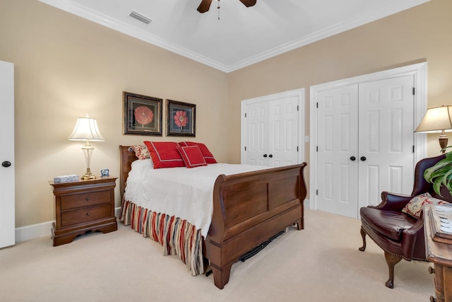 bedroom featuring multiple closets, ornamental molding, light carpet, and ceiling fan