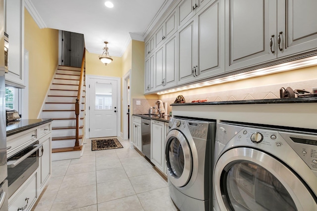 clothes washing area featuring ornamental molding, sink, light tile patterned floors, and independent washer and dryer