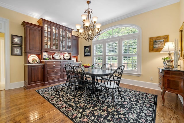 dining area featuring crown molding, a notable chandelier, and light hardwood / wood-style flooring