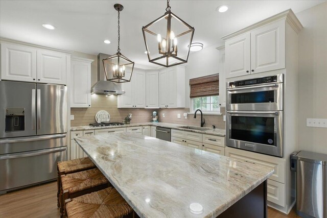 604 Judson Dr, Perry, FL 32348 - kitchen featuring appliances with stainless steel finishes, a sink, a chandelier, wall chimney exhaust hood, and backsplash